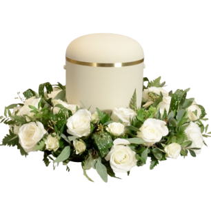 Vit urna omgiven av en krans av vita rosor och gröna blad.
